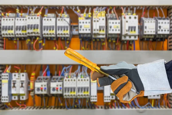 Hand in glove holding screwdriver with control panel cabinet — Stock Photo, Image