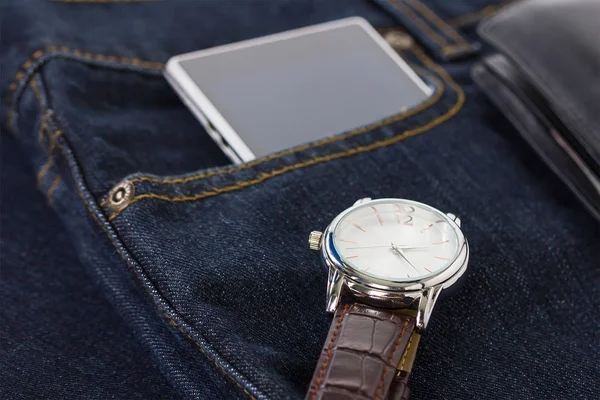 Armbandsur och smartphone på denim jeans — Stockfoto