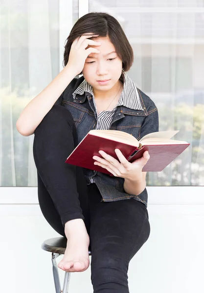 Junge Frau liest Buch auf Stuhl sitzend — Stockfoto