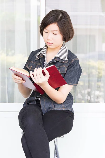 Mujer joven leyendo libro sentado en la silla —  Fotos de Stock