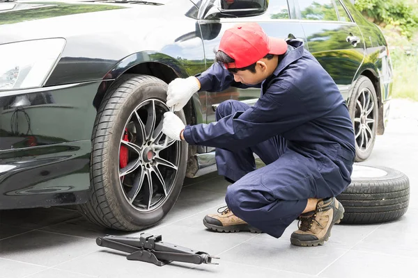 Mechanik nahrazení hlavami šroubů změnu pneumatiky na vozidle — Stock fotografie