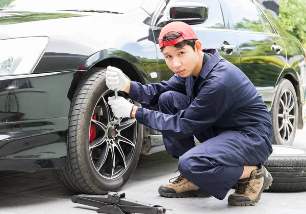 Meccanico sostituzione dadi aletta cambio pneumatici sul veicolo — Foto Stock
