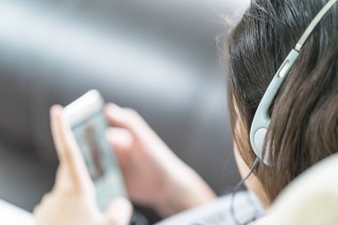 Asyalı kadın cep telefonu üzerinden müzik dinleme
