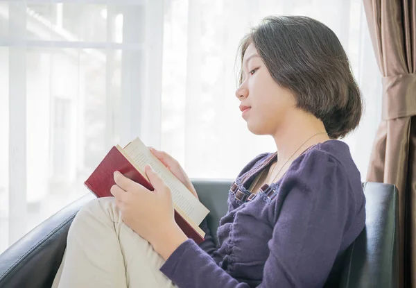 Giovane donna asiatica capelli corti leggere un libro in soggiorno — Foto Stock