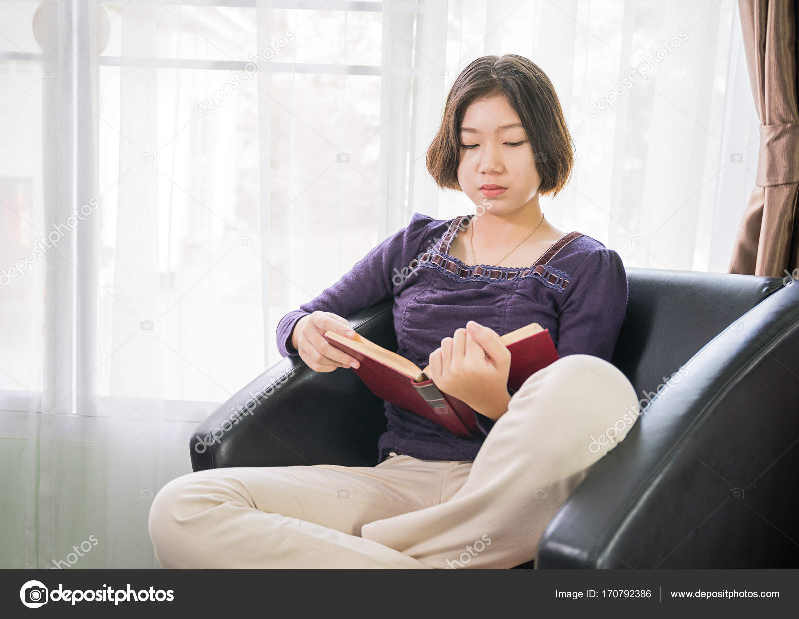 Young Asian Woman Short Hair Read A Book In Living Room Stock