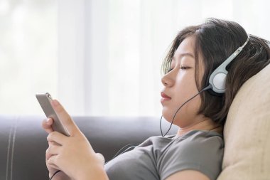 Asyalı kadın cep telefonu üzerinden müzik dinleme