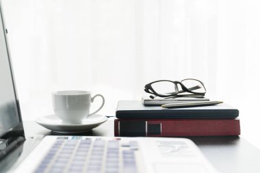Laptop üstünde okul sırası ile kahve fincanı yerleştirilir