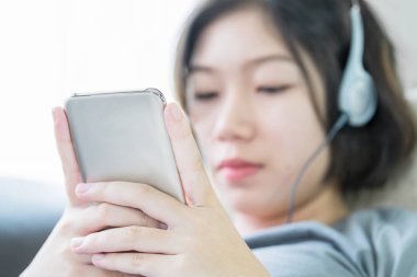 Asyalı kadın cep telefonu üzerinden müzik dinleme