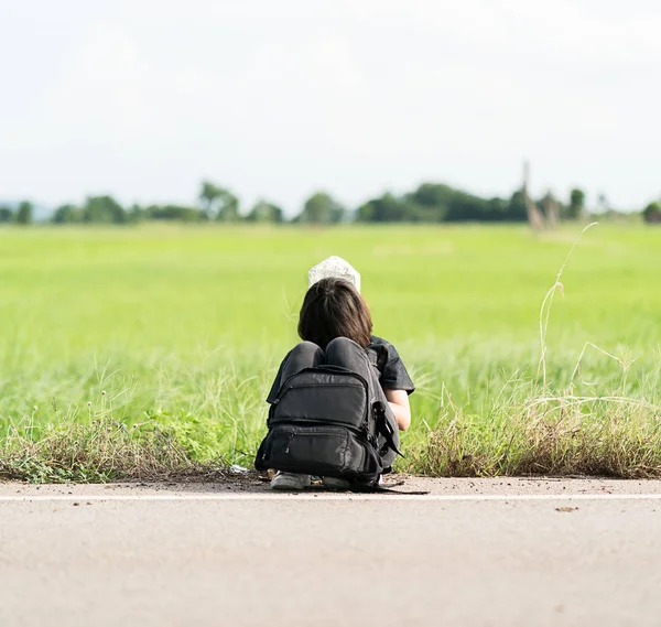 Frau sitzt mit Rucksack auf einer Straße — Stockfoto