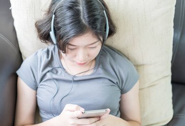 Cep telefonundan müzik dinleyen genç bir kadın.