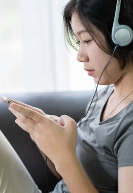 Cep telefonundan müzik dinleyen genç bir kadın.