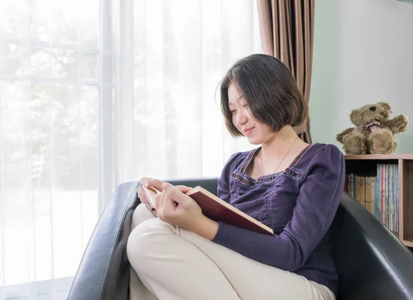 Young asian woman short hair read a book in living room — Stock Photo, Image