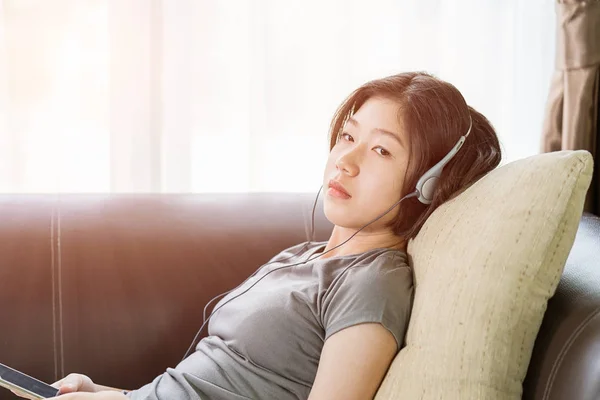 Ung kvinna lyssnar musik från mobiltelefon — Stockfoto
