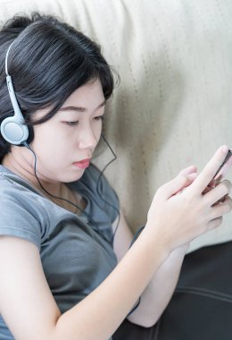 Asyalı kadın cep telefonu üzerinden müzik dinleme