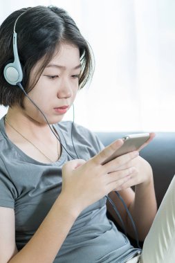 Cep telefonundan müzik dinleyen genç bir kadın.