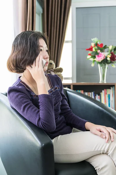 Wanita asia muda rambut pendek menggunakan ponsel di ruang tamu — Stok Foto