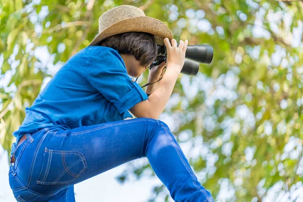 Närbild kvinna bära hatt och håll kikare i gräsplan — Stockfoto