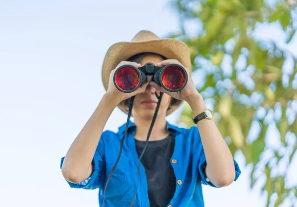 Närbild kvinna bära hatt och håll kikare i gräsplan — Stockfoto