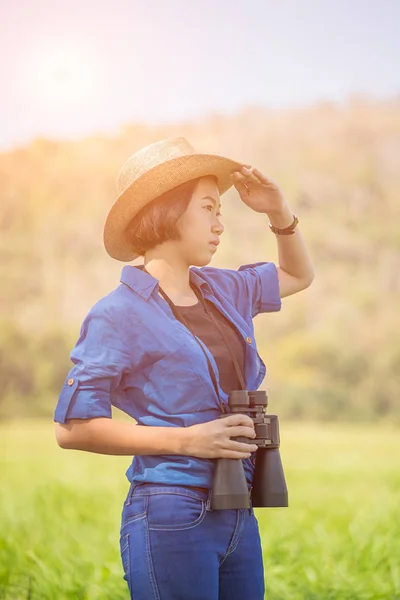 Kvinna bära hatt och håll kikare i gräsplan — Stockfoto