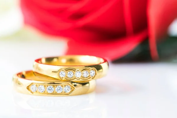 Feche as rosas vermelhas e anéis de ouro no branco — Fotografia de Stock