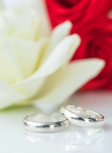 Κόκκινο τριαντάφυλλο και το γαμήλιο δαχτυλίδι σε λευκό — Φωτογραφία Αρχείου
