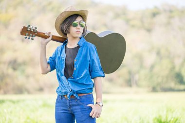 Kadın şapka Tak ve onun gitar çim alandaki taşımak 