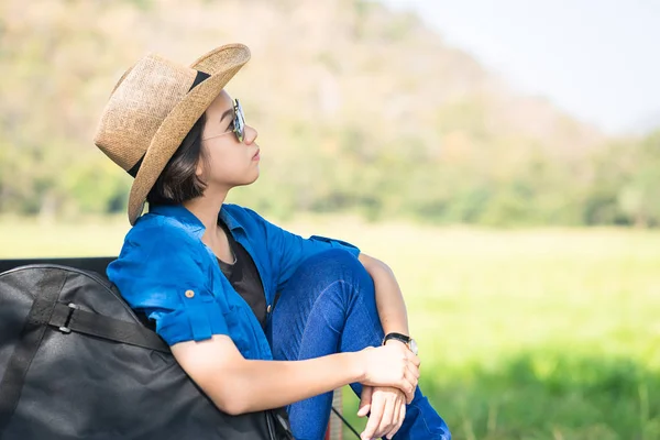 Woman wear hat and carry her guitar bag on pickup truck — Stock Photo, Image