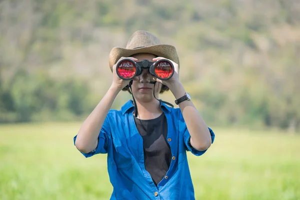 Mujer usar sombrero y mantener binocular en el campo de hierba —  Fotos de Stock