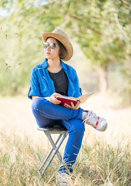 Γυναίκα φορούν καπέλο και την ανάγνωση του βιβλίου στην καρέκλα — Φωτογραφία Αρχείου