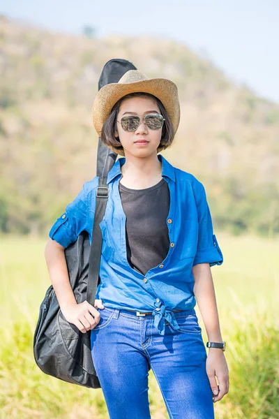 Mujer usar sombrero caminando y llevar su bolsa de guitarra —  Fotos de Stock