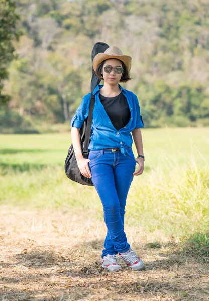 Mujer usar sombrero caminando y llevar su bolsa de guitarra —  Fotos de Stock