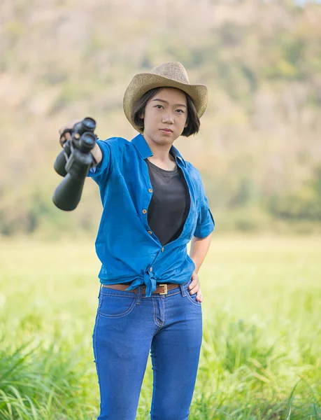 Mujer usar sombrero y mantener binocular en el campo de hierba —  Fotos de Stock