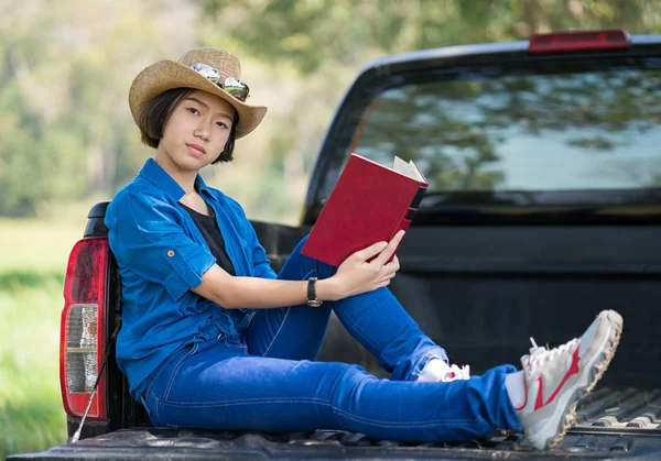 Woman wear hat and reading the book on pickup truck — Stock Photo, Image