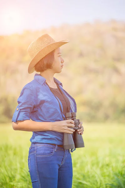 Kvinna bära hatt och håll kikare i gräsplan — Stockfoto