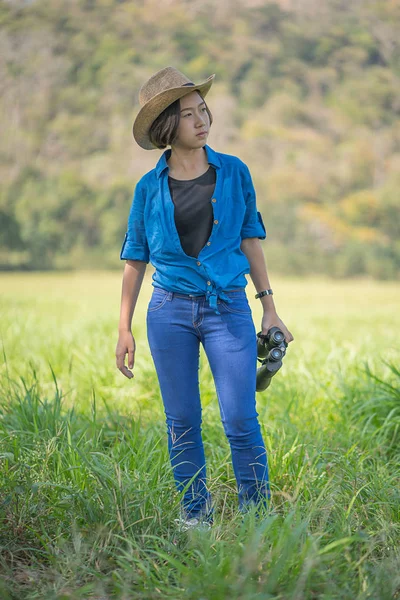 Woman wear hat and hold binocular in grass field — Stock Photo, Image