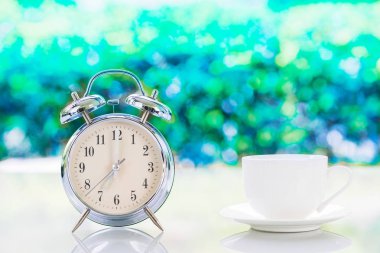 Gümüş alarm saati ve beyaz kahve fincanı.