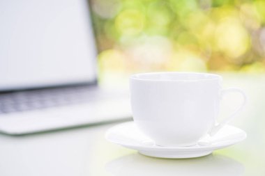 Ofiste Bokeh 'le kahve fincanı ve dizüstü bilgisayar.