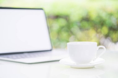 Ofiste Bokeh 'le kahve fincanı ve dizüstü bilgisayar.