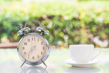 Gümüş alarm saati ve beyaz kahve fincanı.