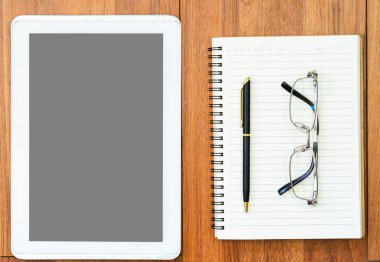 Dijital tablet, ahşap güvertede gözlük ve not defteri ile taklit edilir.