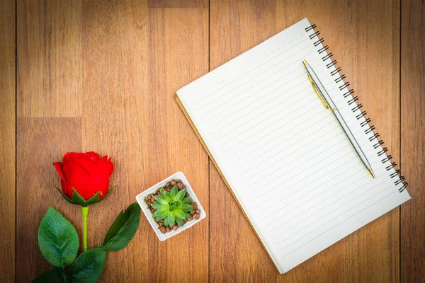 Red roses on wooden table and notepad — Stock Photo, Image