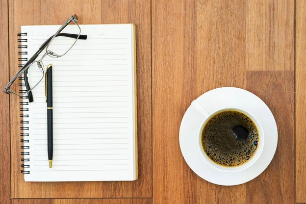 Eyeglasse and notepad with coffee cup on wood deck — Stock Photo, Image