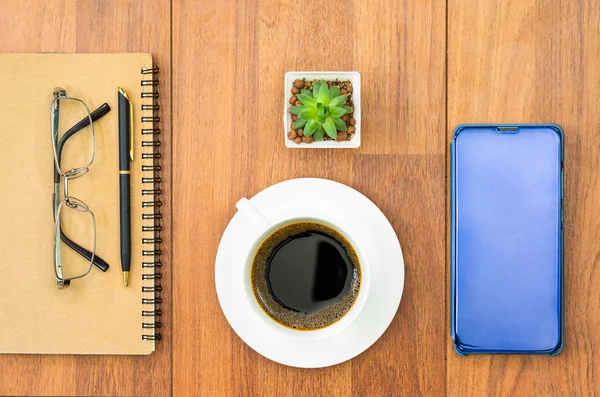 Imagem de vista superior de xícara de café e celular na mesa de madeira — Fotografia de Stock