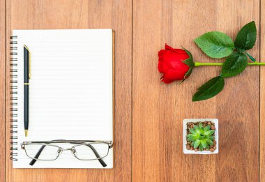 Ahşap masa ve not defterinde kırmızı güller