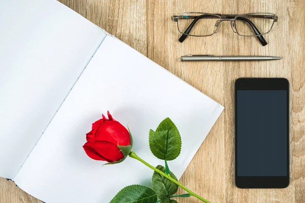 Rote Rosen auf blankem Notizbuch-Tagebuch mit Smartphone — Stockfoto