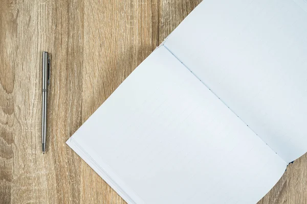 木のテーブルの上に銀ペンと空白のノートブック日記 — ストック写真