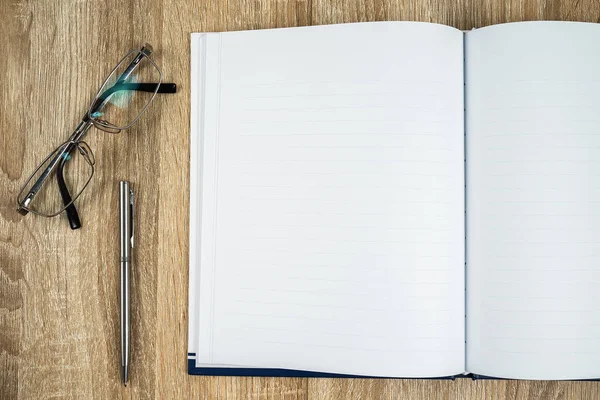 Blanco notitieboekje met zilveren pen en bril — Stockfoto