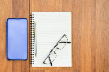 Boş sayfa ve cep telefonlu açık defterin üst görünüm resmi