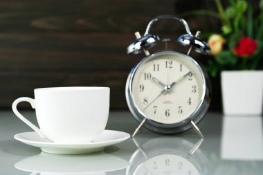 Kahve fincanı ve çalar saat masanın üstünde.