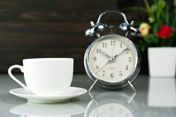 Coffee cup and alarm clock on table — 스톡 사진